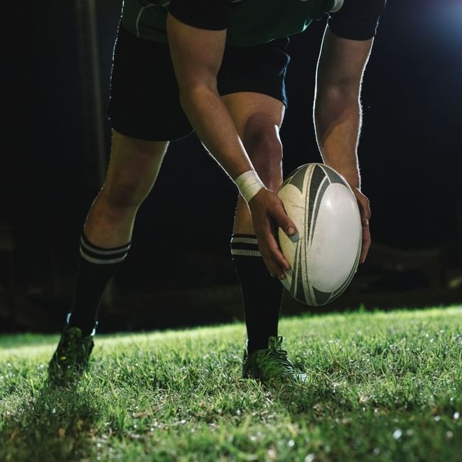 Rugby player holding ball on illuminated field at night for Bledisloe Cup Dining experience