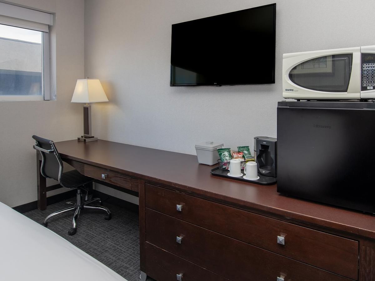 Room with desk, TV, microwave, and fridge.