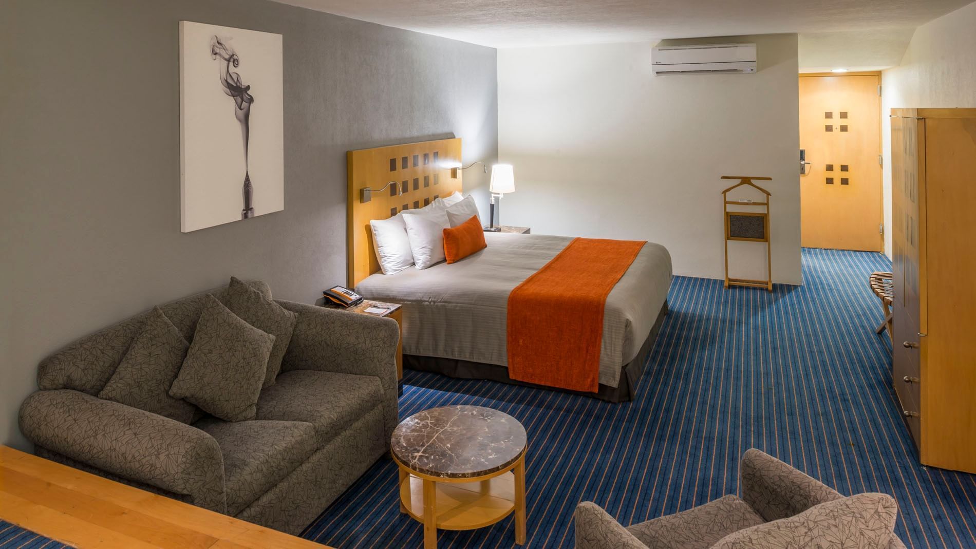 King Deluxe Superior featuring a grey sofa, marble coffee table, and blue striped carpet at Real Inn Nuevo Laredo