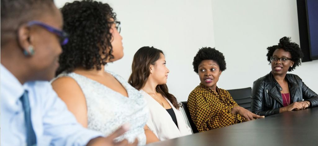 A group of diverse professionals engaged in a discussion around a conference table, collaborating in a business meeting.