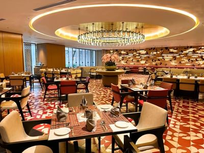 Elegant restaurant interior featuring stylish seating, vibrant flooring, and a large chandelier at One World Hotel