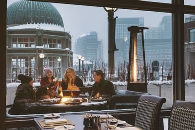 A cluster of guests laughing fireside on the harbor