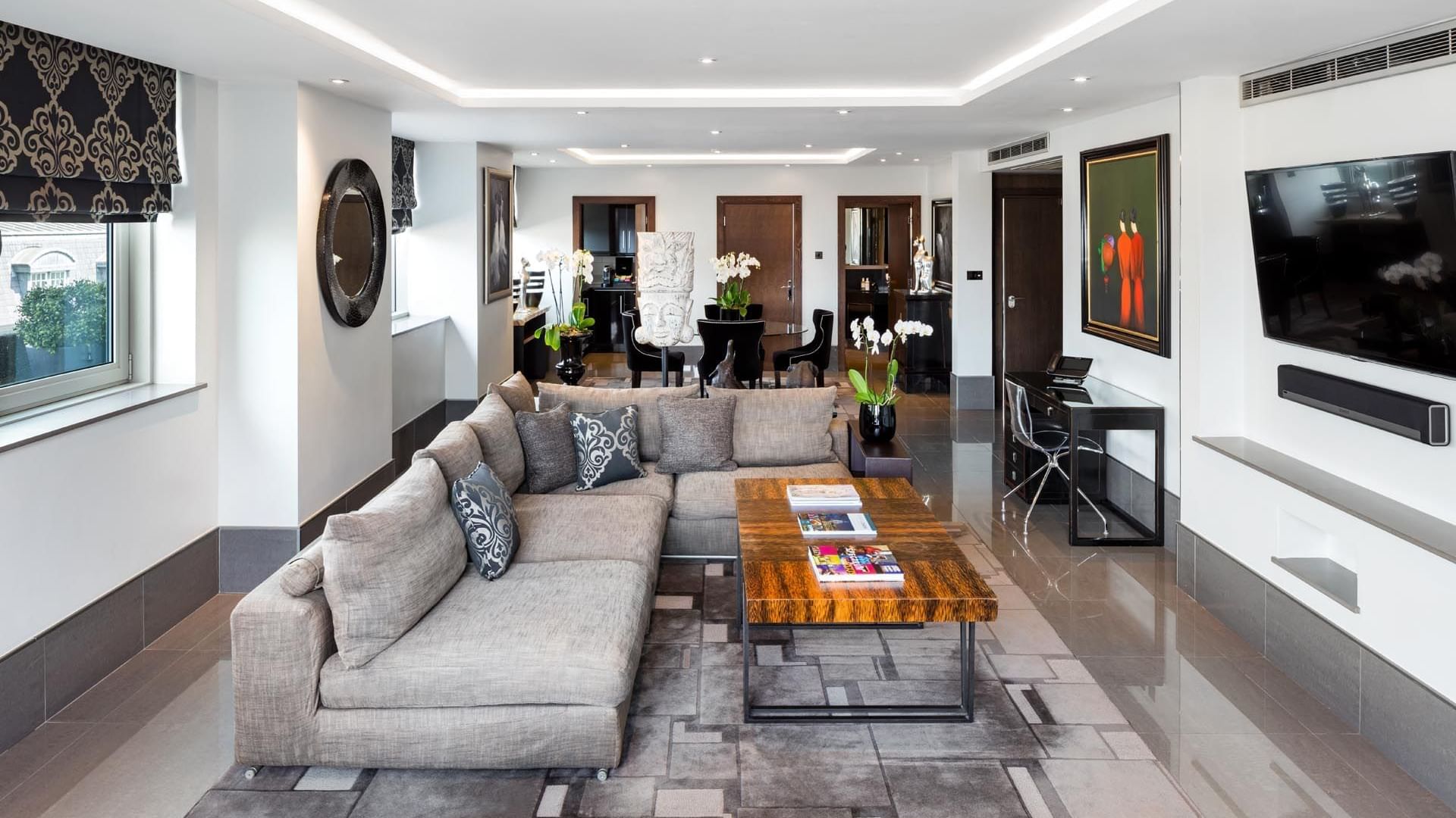 Modern living room in The Ebony Suite at The May Fair Hotel, London, featuring a sectional sofa and a wooden coffee table