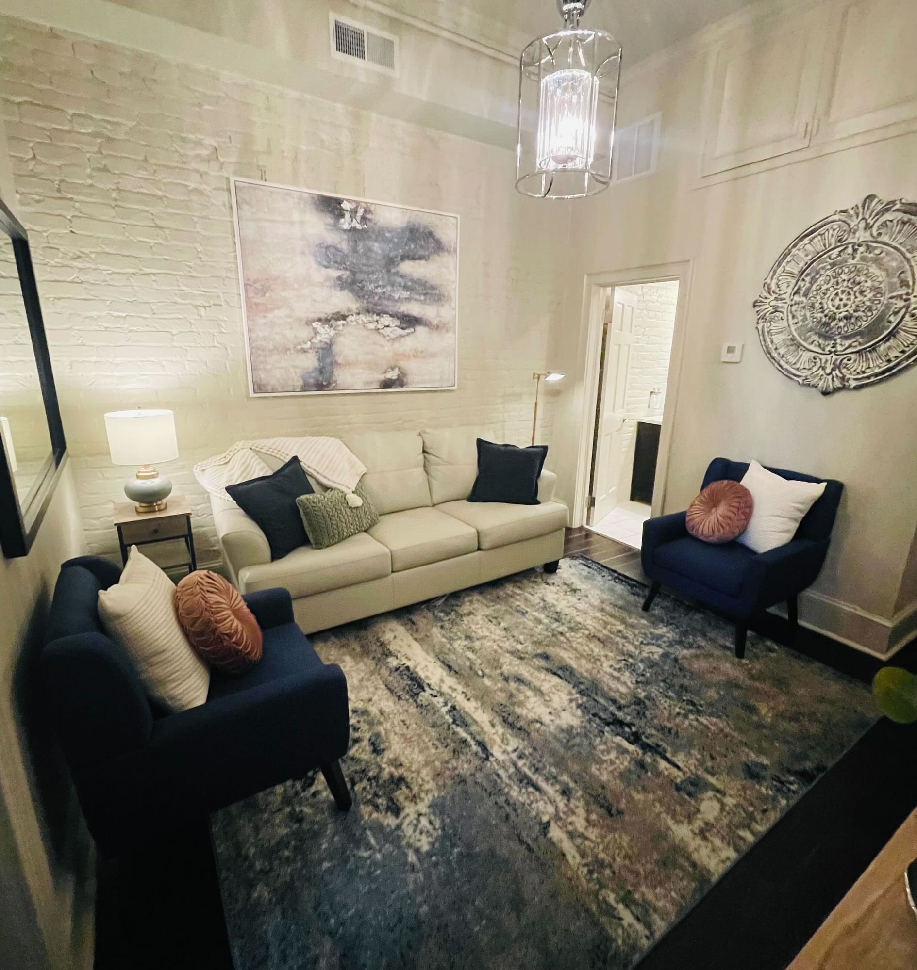 A wide view of a junior suite's sitting area with a sofa, two armchairs, and a coffee table on a rug.