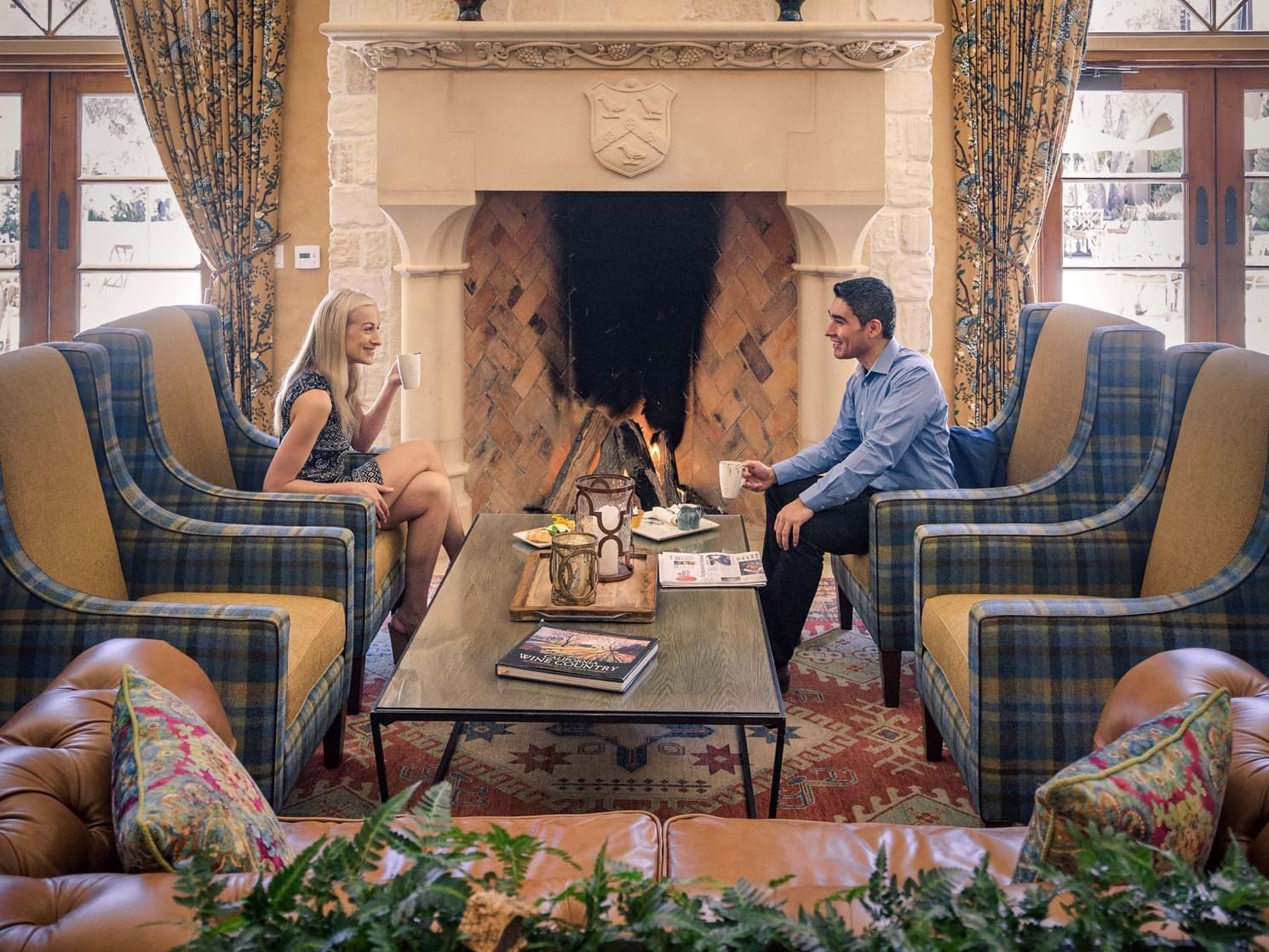 Man and woman sitting in front of fireplace drinking coffee