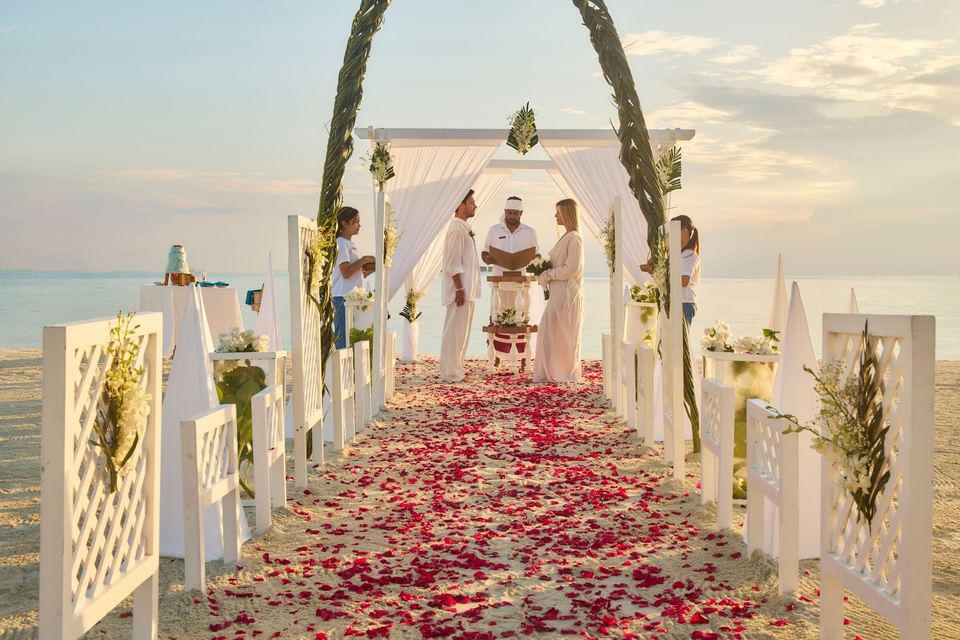Beach wedding ceremony with floral arches and red petals at Grand Park Kodhipparu.