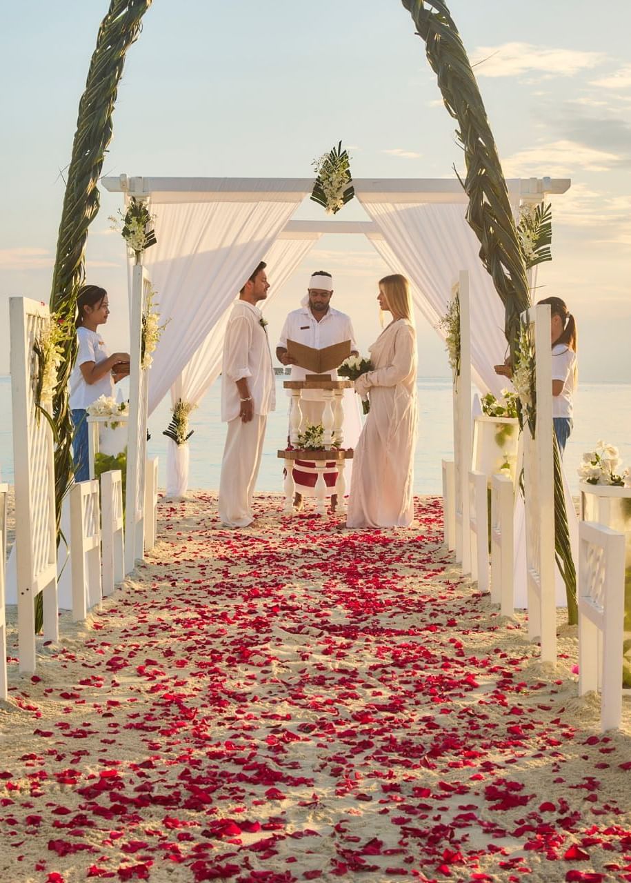 Couple standing under a beach wedding canopy at Grand Park Kodhipparu, Maldives