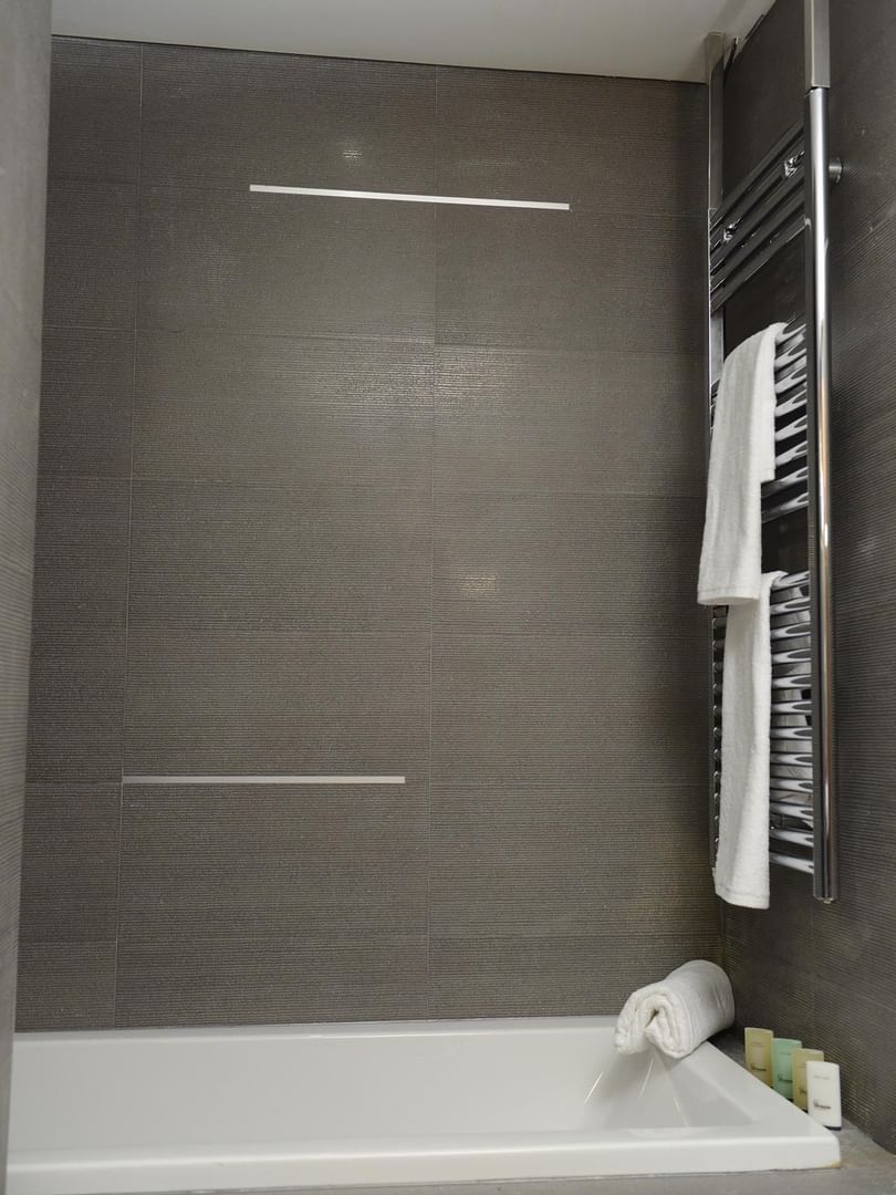 White towels on a heated rack by a grey textured wall in a bathroom in Junior Suite at Warwick Stone 55 - Beirut