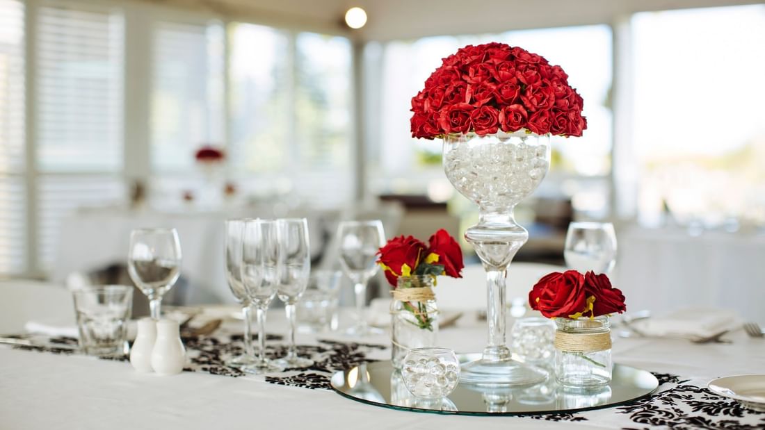 Table setting with a tall vase of red roses and glassware at Mercure Hotel Townsville