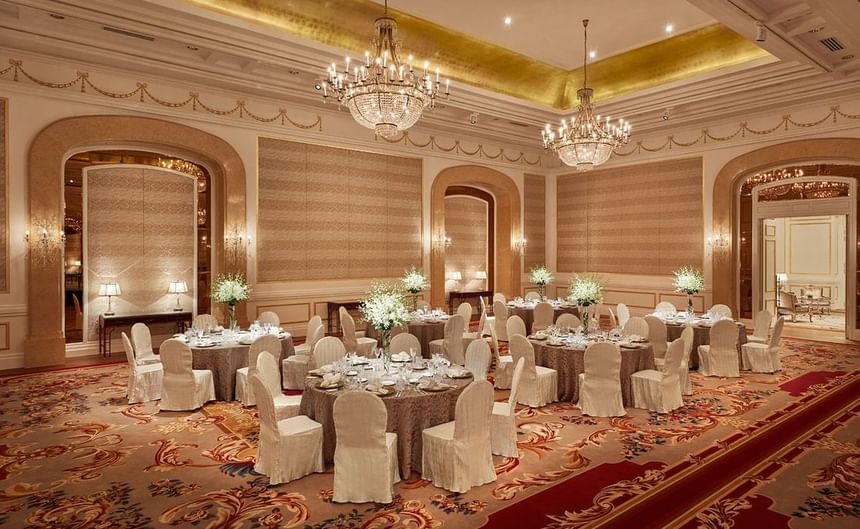 Banquet tables arranged in the Ballroom with carpeted floors and illuminated ceiling at Park Hyatt Saigon