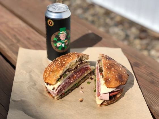 Muffuletta & beer can on a wooden table near The Whittaker Inn