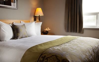 Cozy bed with lamp in Queen Room at Fort McMurray Hotels