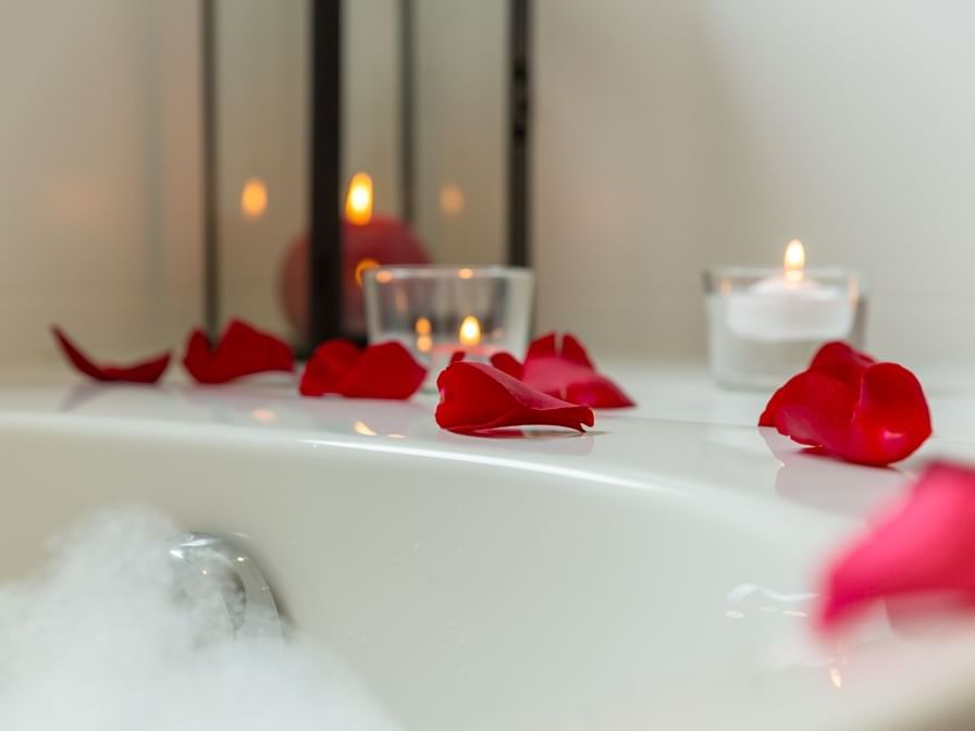 Candles on bathtub filled with foam and rose petals at Armony