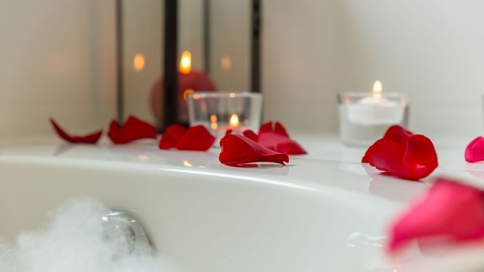 Candles on bathtub filled with foam and rose petals at Armony