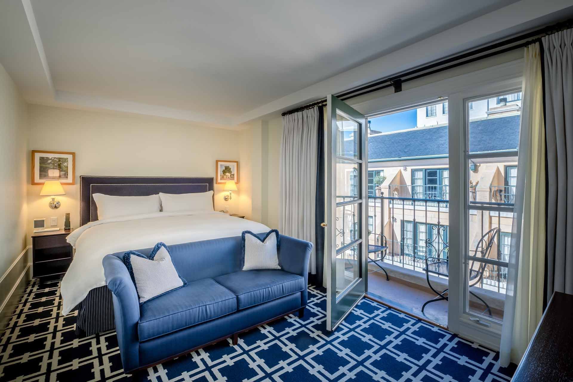 Bed with seating and a private balcony area at El Prado Hotel