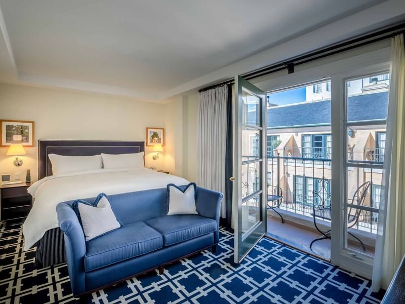 Cozy sofa by the bed in Deluxe Junior King Suite with carpetd floors and private balcony area at El Prado Hotel