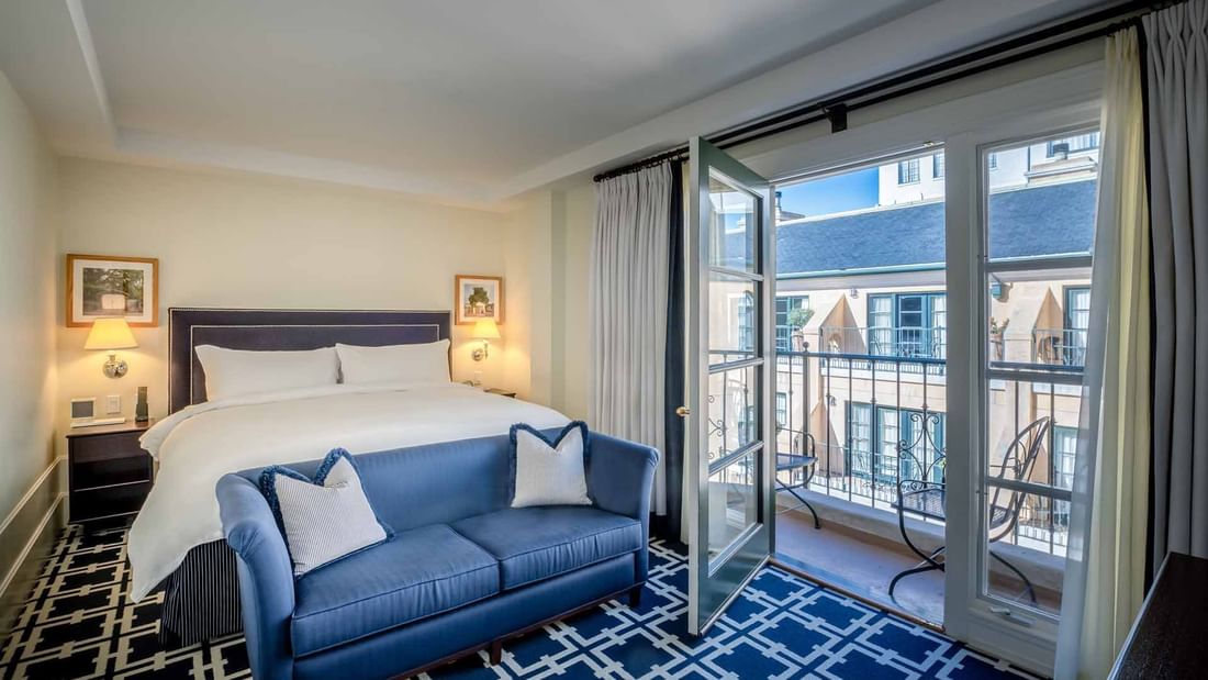 Cozy sofa by the bed in Deluxe Junior King Suite with carpetd floors and private balcony area at El Prado Hotel