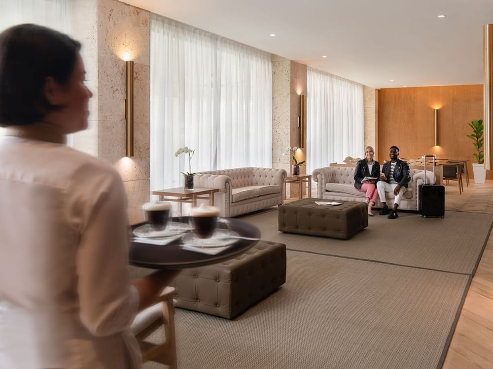 A waiter bringing beverages to a couple at Live Aqua Resorts