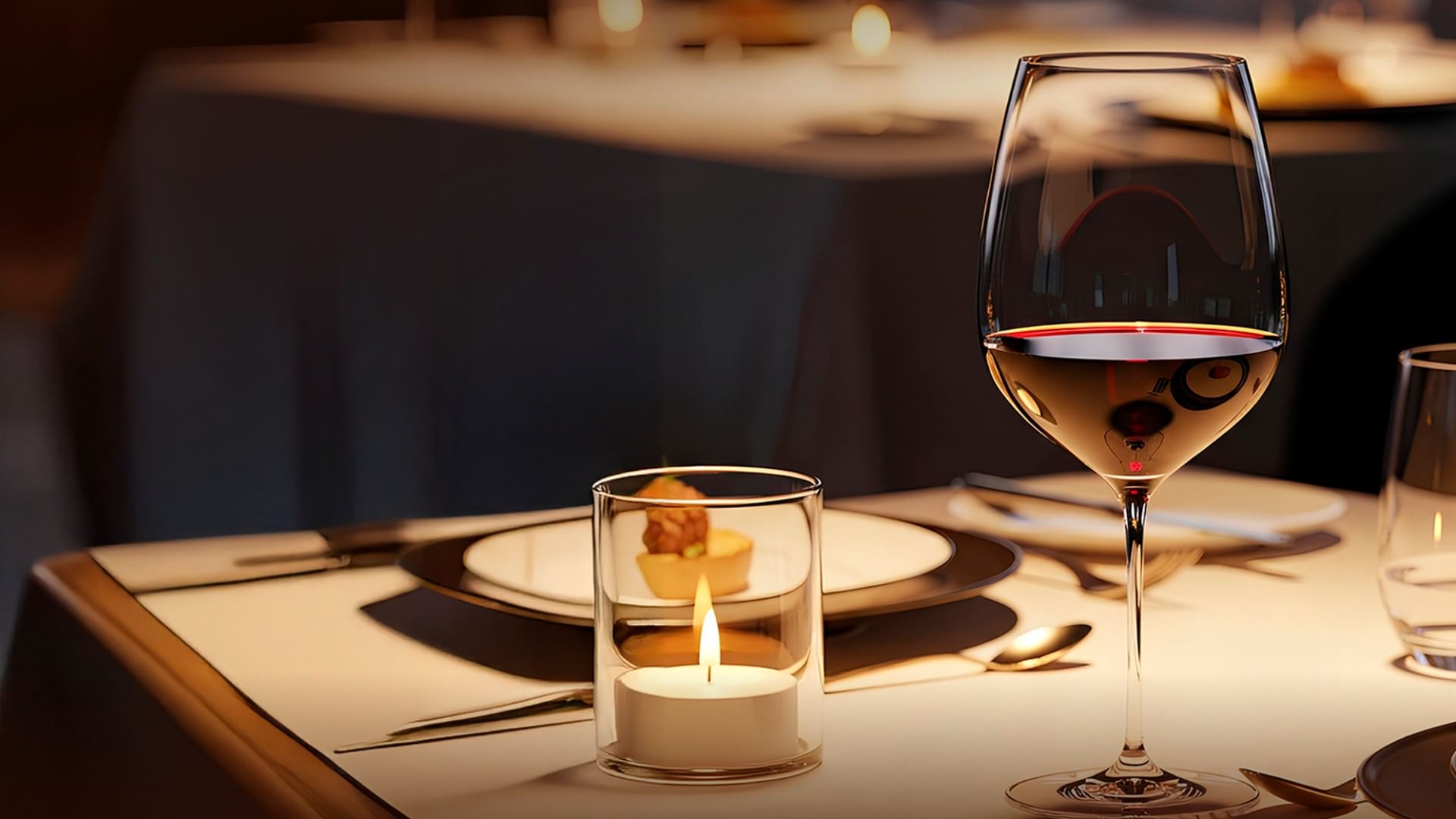 Wine glass and candle on an elegantly set table, conveying a romantic, cozy atmosphere at Camino Real