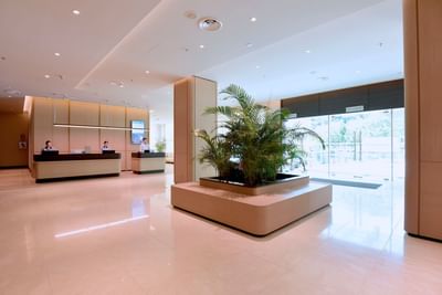 Reception desk by lobby area with marble floors & potted plants at Cititel Express Kota Kinabalu
