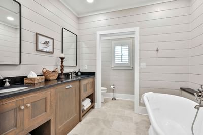 Stylish bathroom with dual sink vanity, modern fixtures, and a white bathtub by Cottages at Laurel Brooke