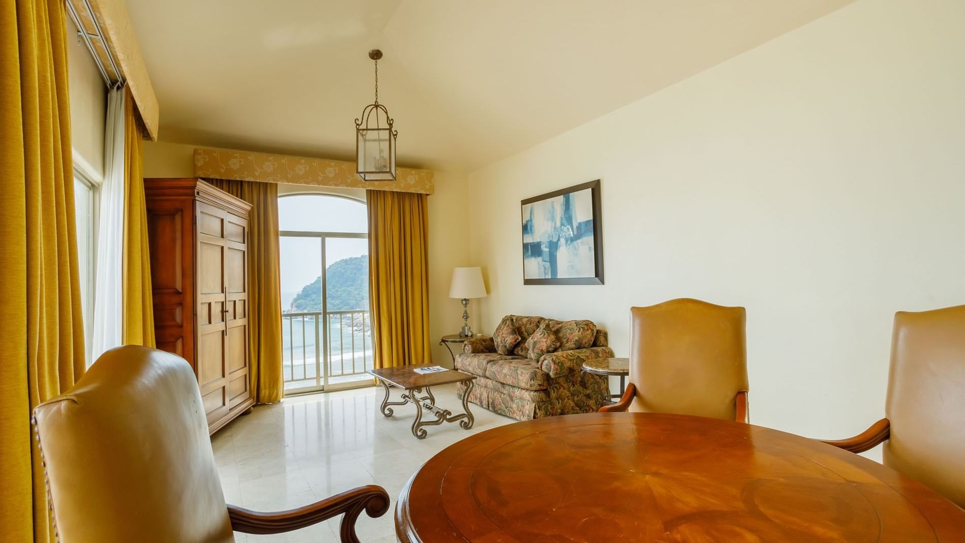 King Governor Suite living area with ocean views, a floral sofa, and classic wooden furniture at Quinta Real Acapulco