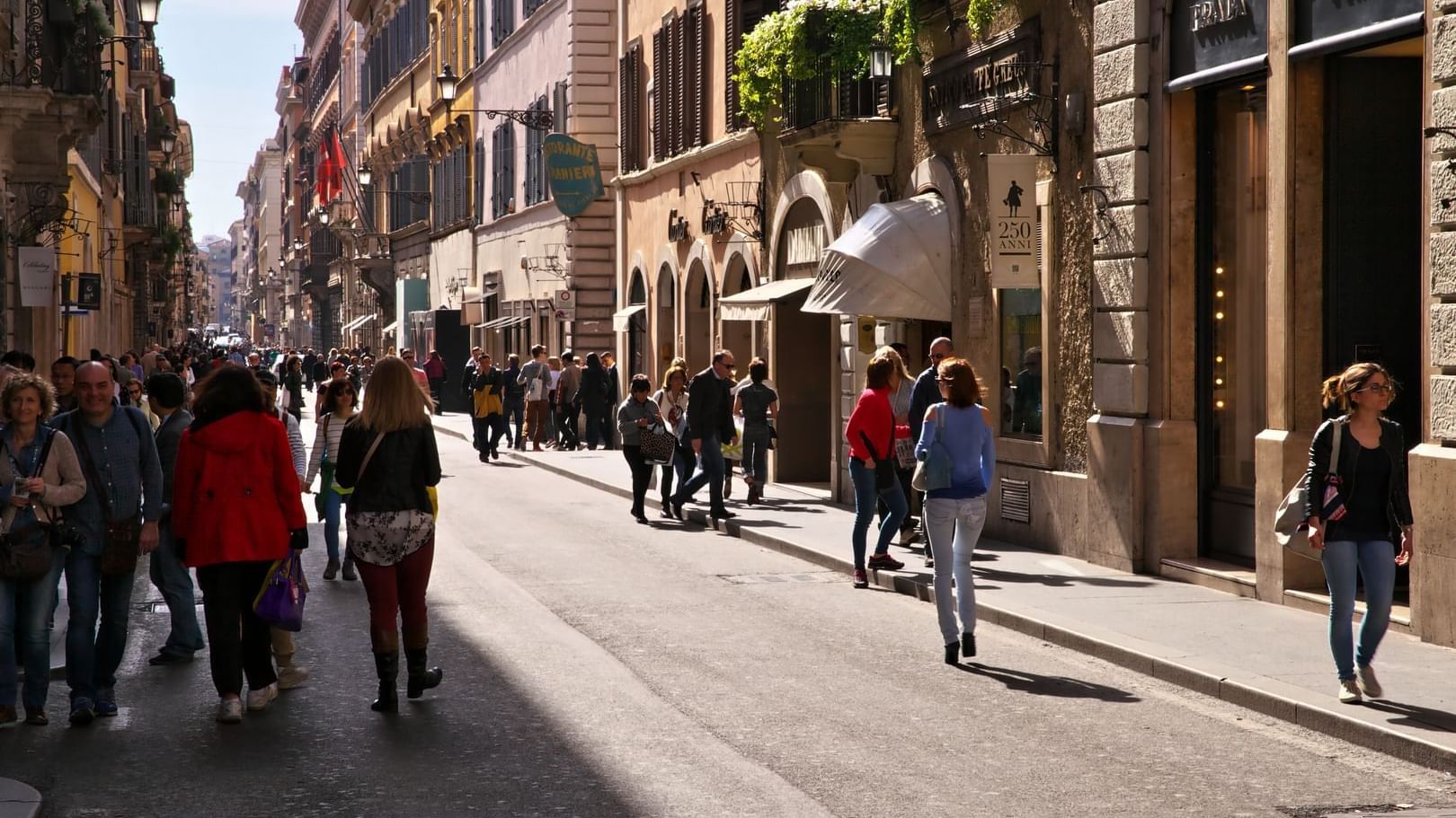 A bustling Roman shopping street filled with tourists and local pedestrians near the exquisite Rome Luxury Suites