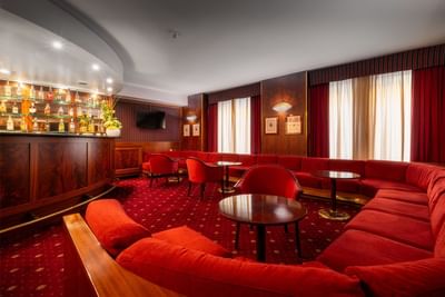 A stylish interior showcasing a red sofa and red chairs in the Bar at Hotel Crivi's in Milan