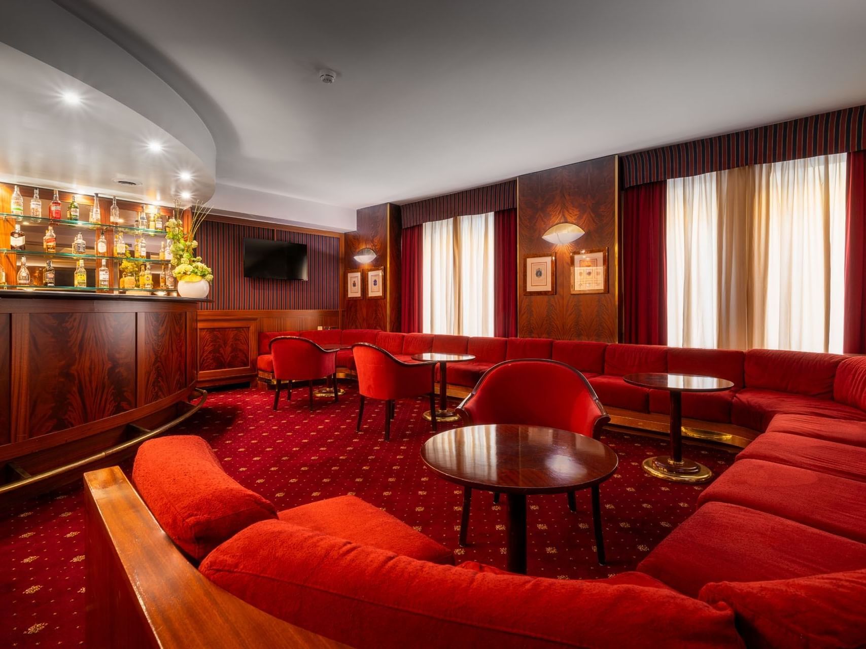 A stylish interior showcasing a red sofa and red chairs in the Bar at Hotel Crivi's in Milan