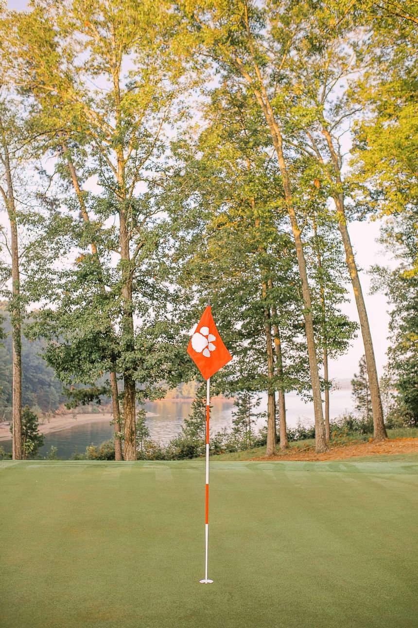 Golf flag with Clemson paw logo on a green course overlooking Lake Hartwell at Clemson University Conference Center & Inn
