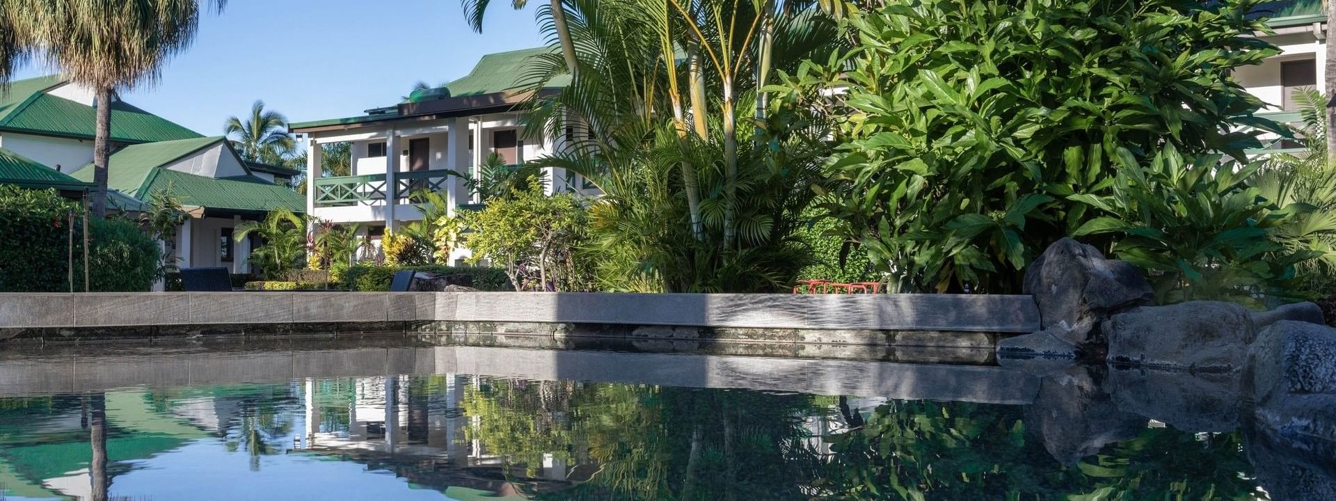 Clear swimming pool surrounded by lush greenery and tropical trees at Tokatoka Resort - Nadi, Fiji.