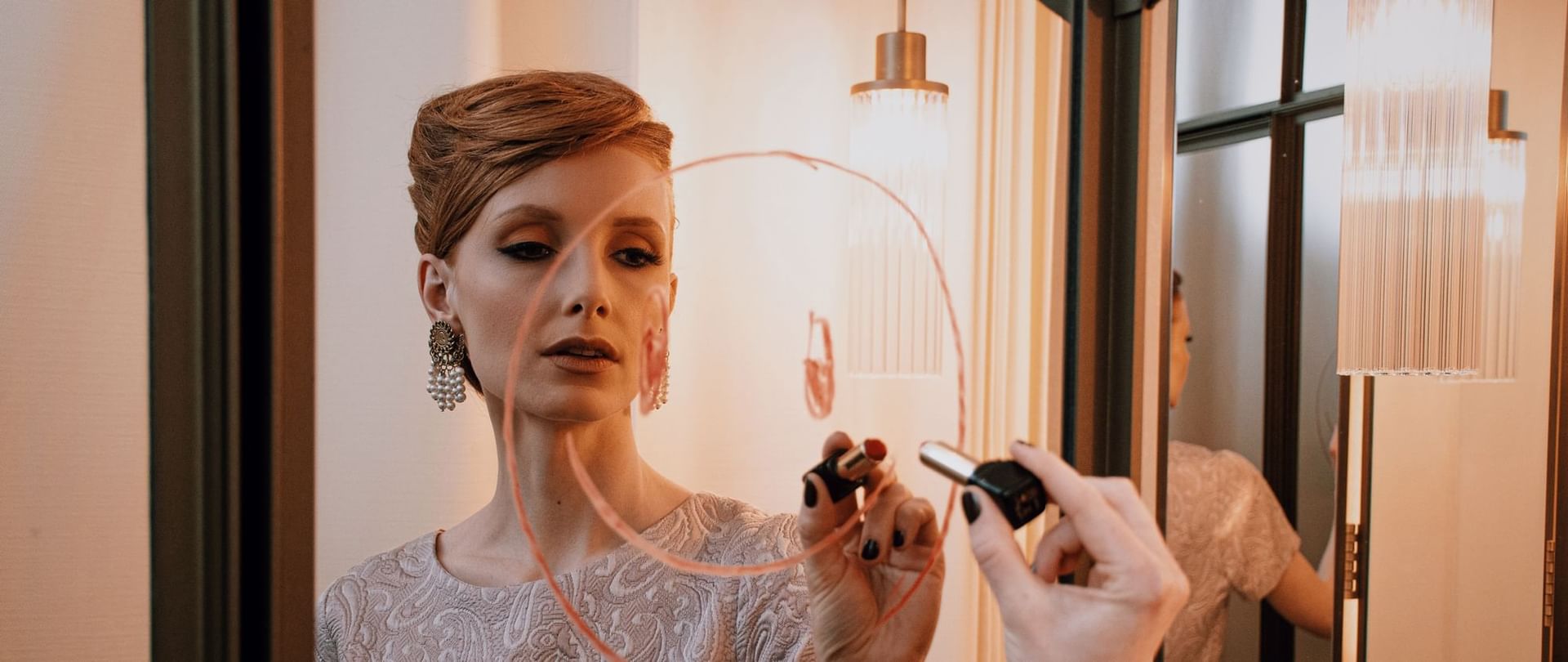 Elegante Frau malt auf Speigel mit Lippenstift im Hotel Motto Vienna