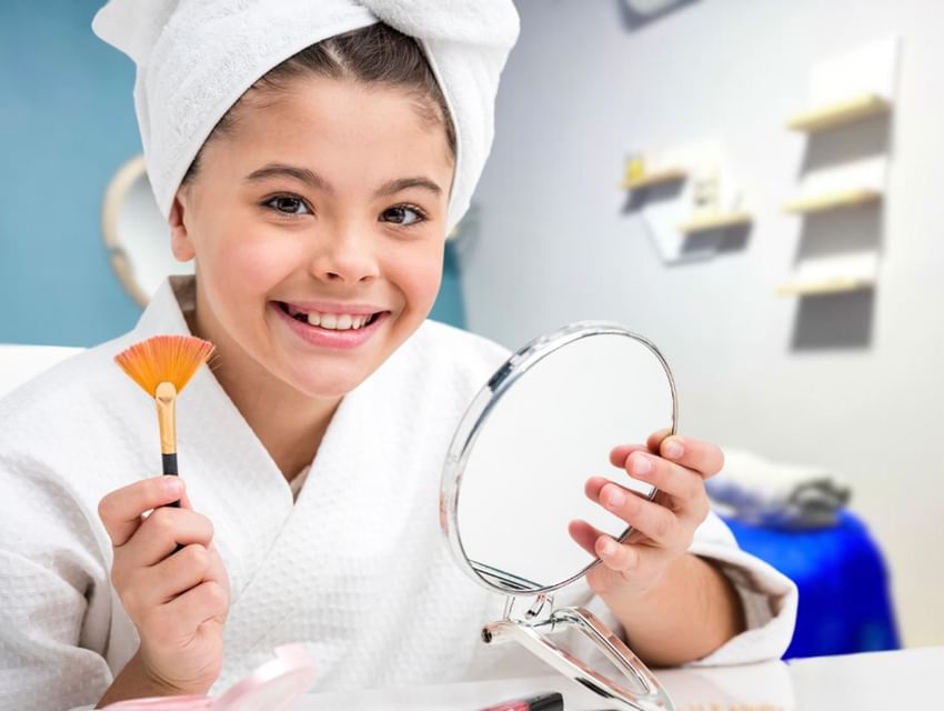 Una chica en toalla sostiene un brocha y un espejo en el Hotel San Fernando Plaza