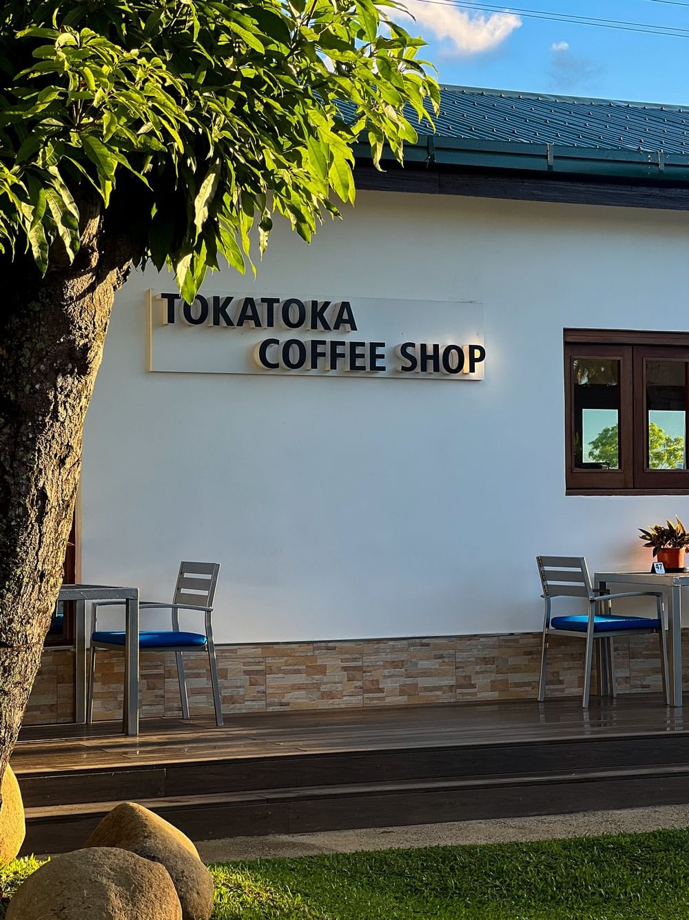 Outdoor seating with blue cushions and Tokatoka Coffee Shop sign at Tokatoka Resort - Fiji International Airport.