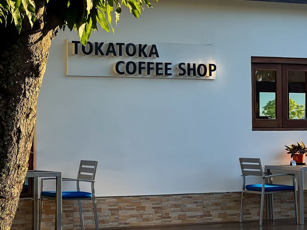 Outdoor seating with blue cushions and Tokatoka Coffee Shop sign at Tokatoka Resort - Fiji International Airport.