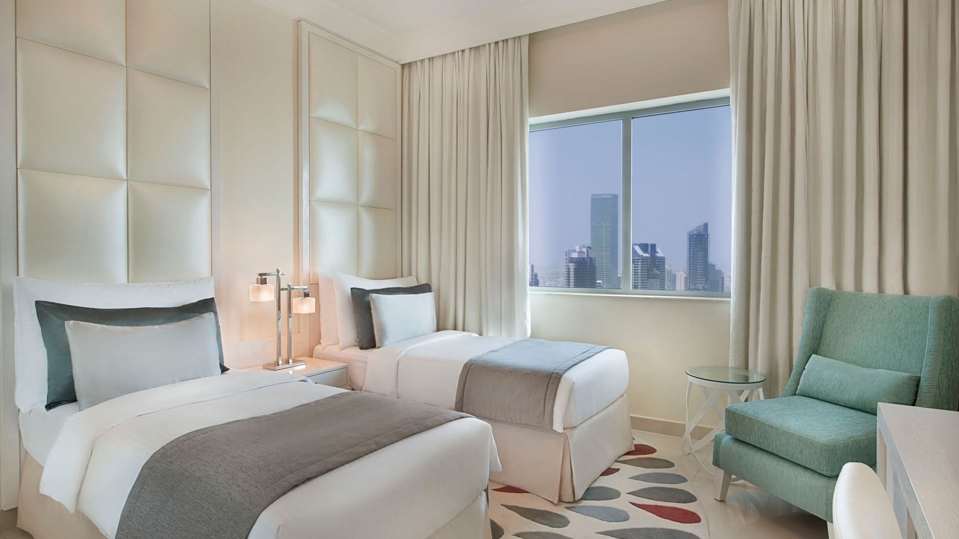 2 Comfy beds with side table, chair and city view in Two Bedroom Suite at DAMAC Maison Dubai Mall Street