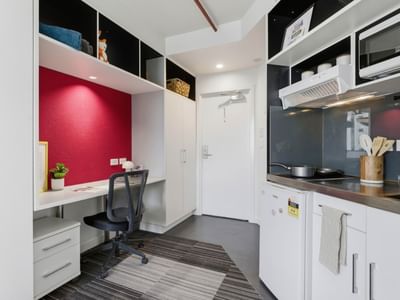 White kitchen with desk and chair at UniLodge Auckland City.
