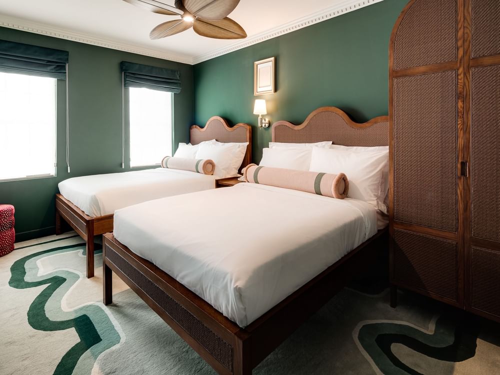 A hotel room with two twin beds, green walls, and a wavy rug