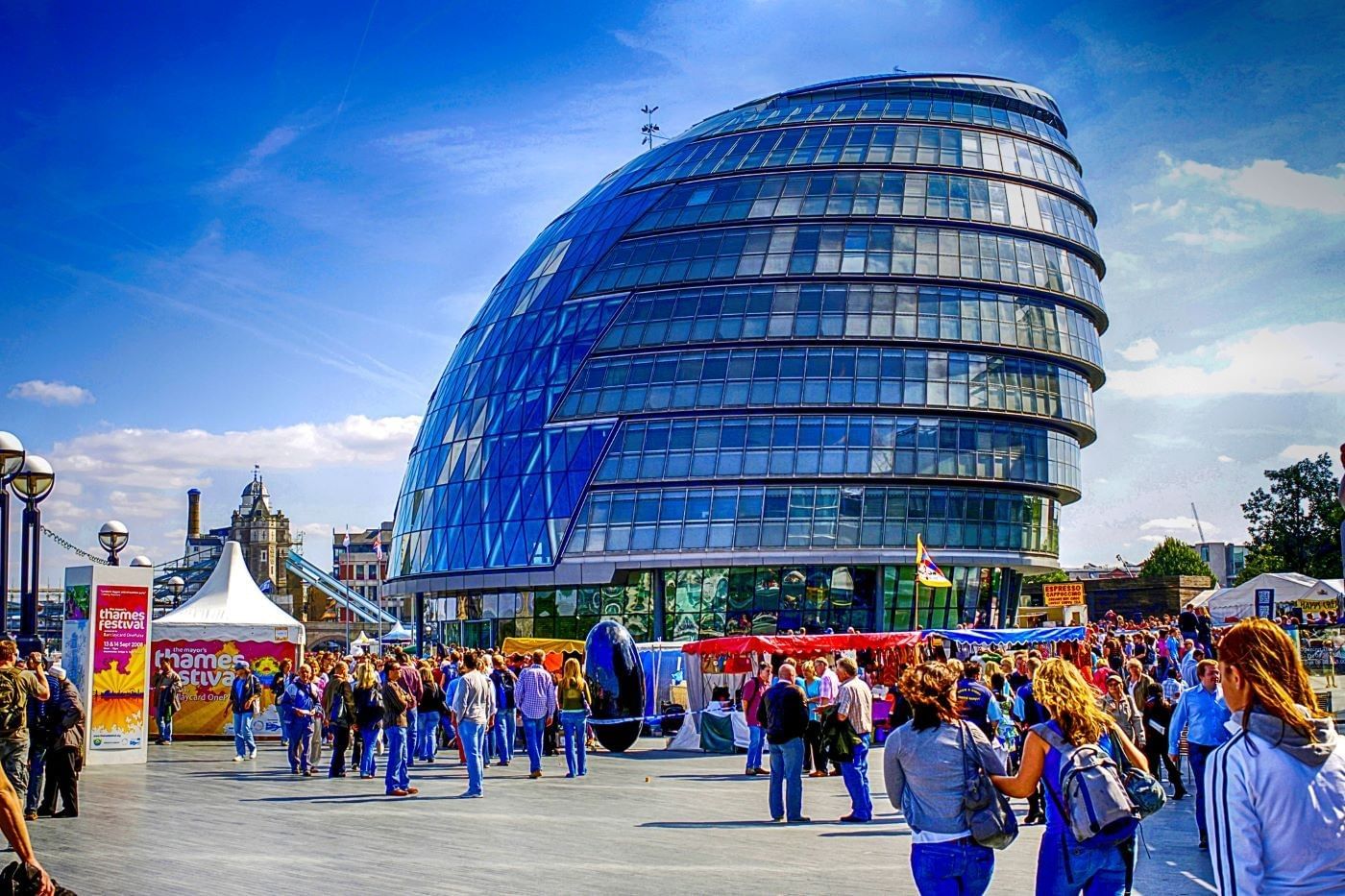 Futuristic glass building overlooking a lively outdoor festival by the Thames, near The Londoner