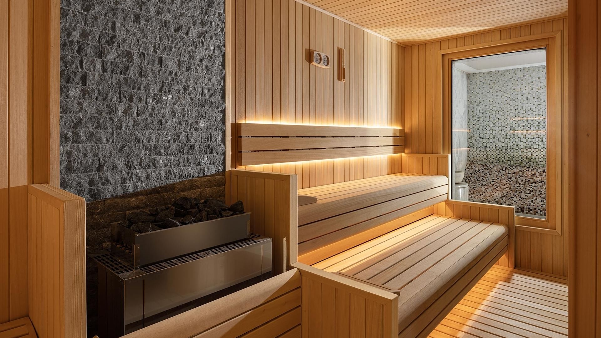 Wooden sauna with benches, a gray stone wall in Befine Spa at Titanic Business Kartal