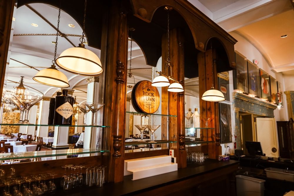 Martini glasses by a wooden barrel under hanging dome lights in the Venetian Dining Room at Arlington Resort Hotel & Spa