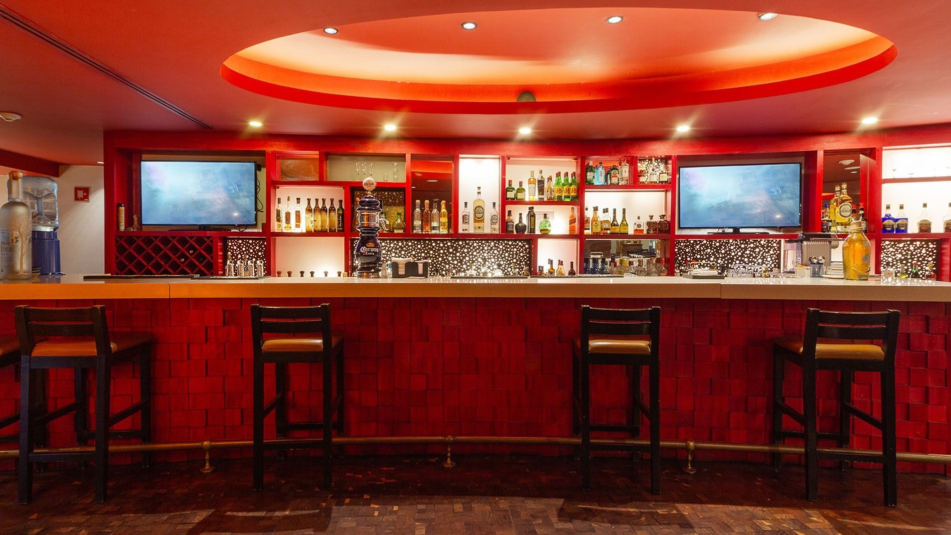 Modern Maria Bonita bar featuring red accents, ambient lighting, and a well-stocked shelf at Camino Real Guadalajara