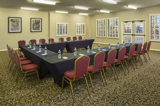 Meeting room with U-shaped table setup, burgundy chairs, and water bottles at London Bridge Resort