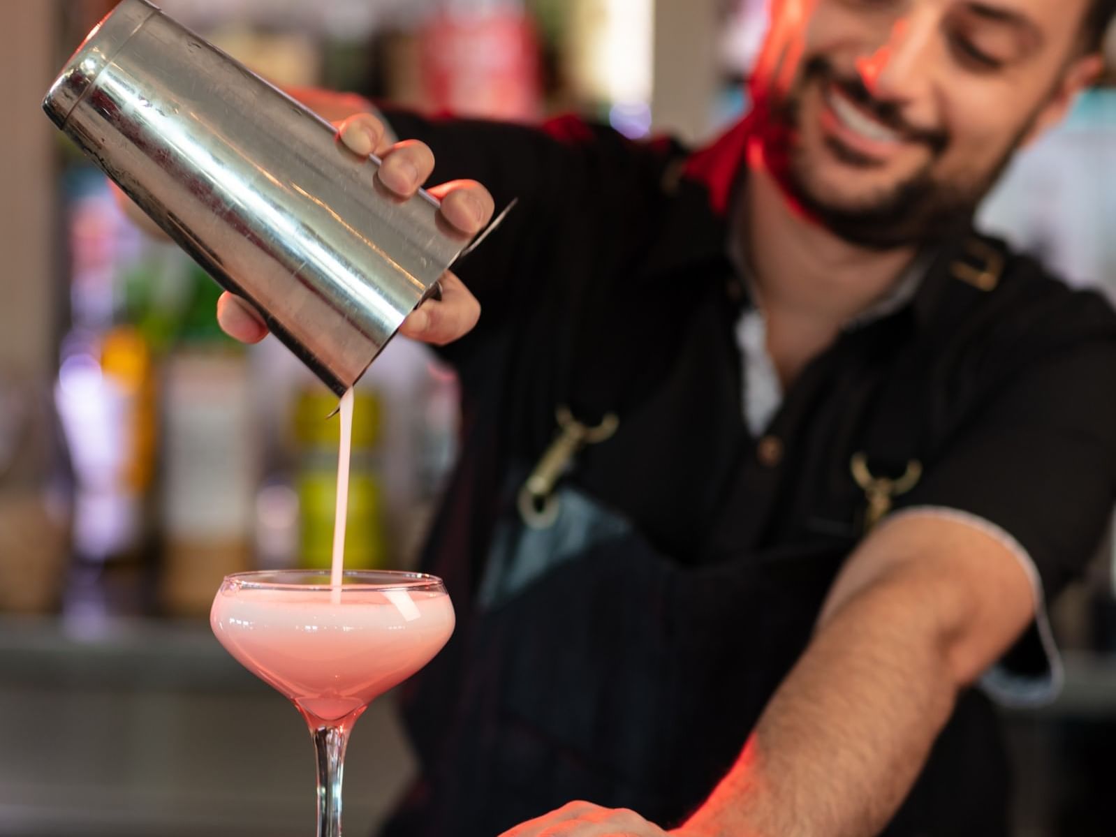 Bartender pouring pink cocktail