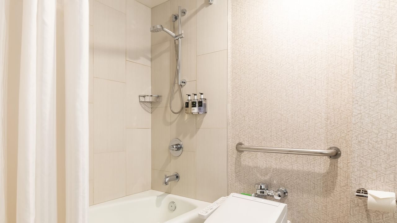 A hotel bathroom with a bathtub, removable shower head, and toilet.