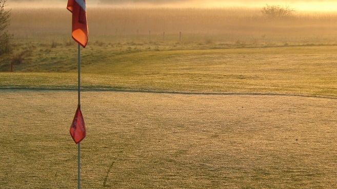 Sunrise view of Kogarah Golf Club with misty fairways and red flag, near Novotel Sydney International Airport