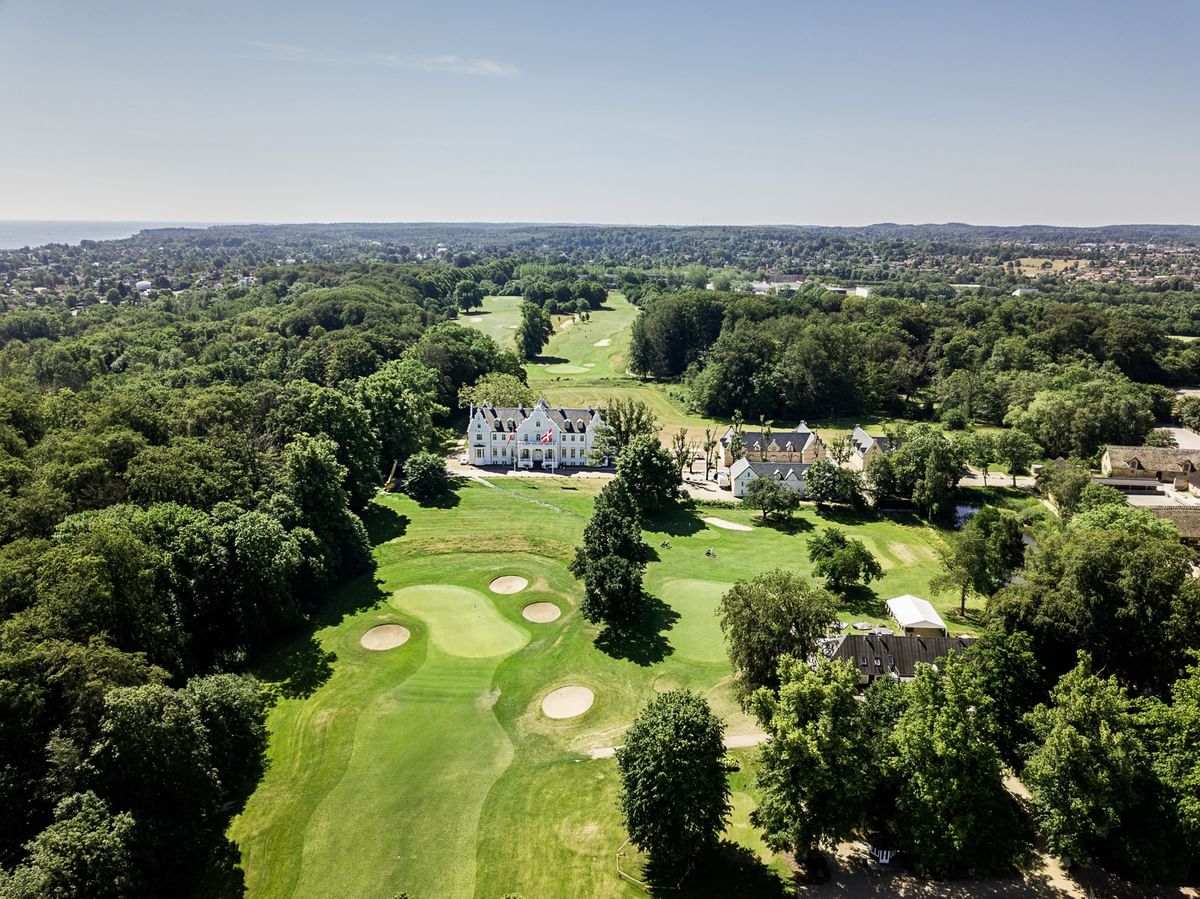 High-angle aerial view of Warwick Denmark hotel surrounded by a lush green golf course
