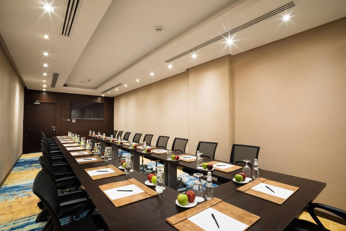 U-shaped table setup facing hanging TV in Khalej Meeting Room at Naviti by Warwick Dammam
