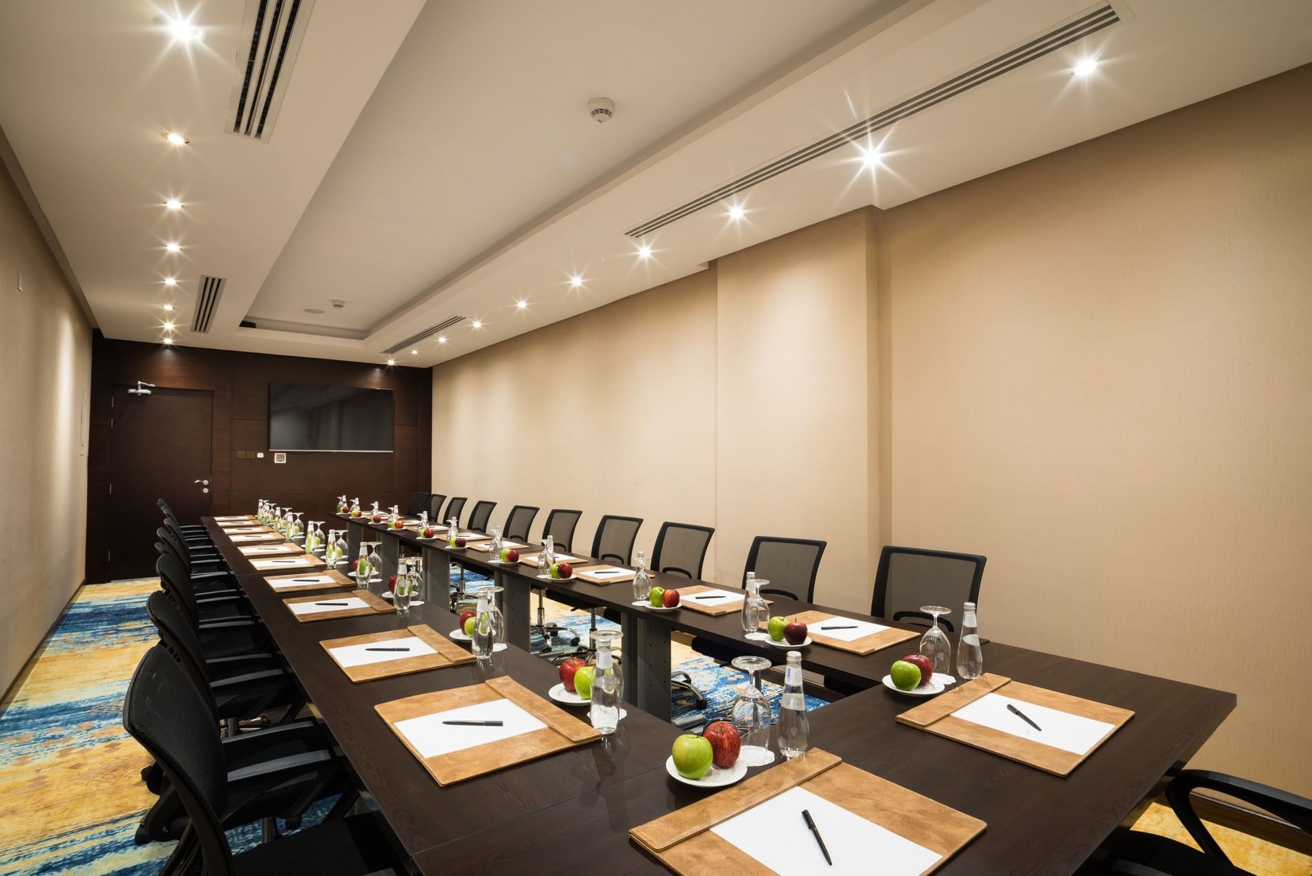 U-shaped table setup facing hanging TV in Khalej Meeting Room at Naviti by Warwick Dammam