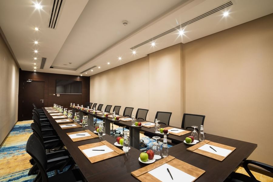U-shaped table setup facing hanging TV in Khalej Meeting Room at Naviti by Warwick Dammam
